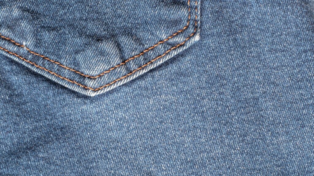 Close-up denim seam and pocket, illustrating trouser construction