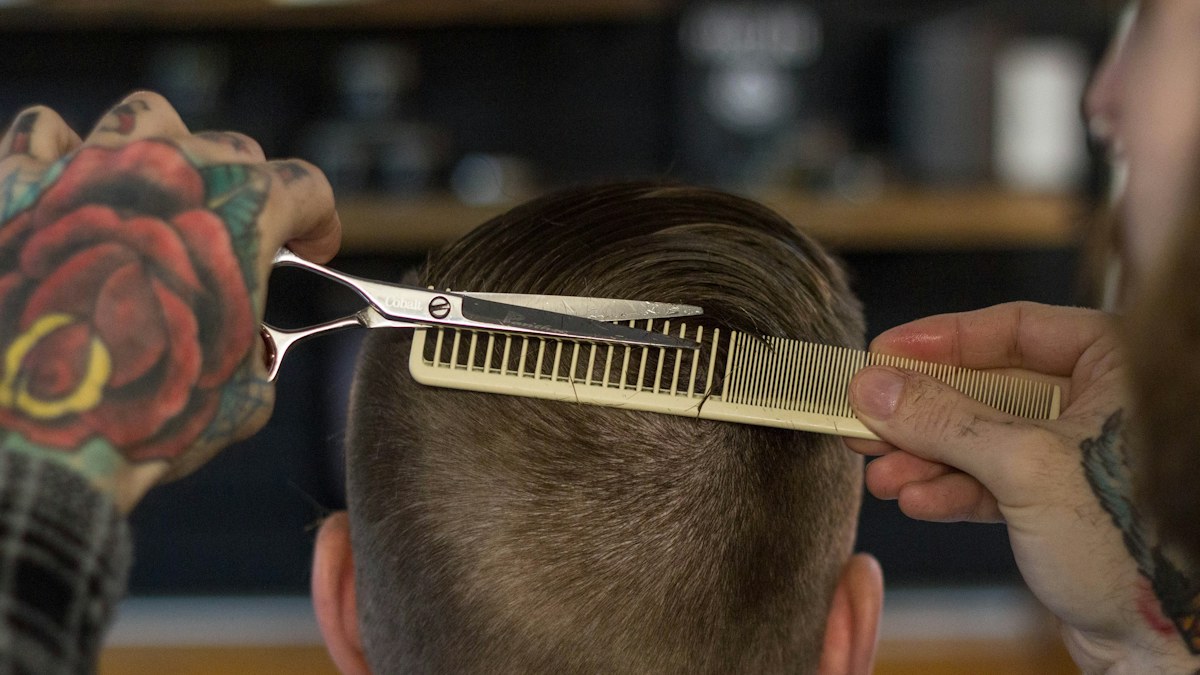 Hand holding a white and gold hair comb