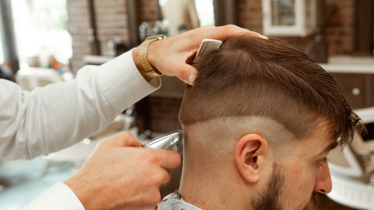 Barber cutting a man's hair in a shop