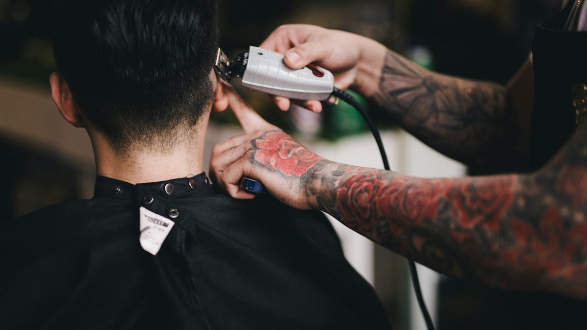 Barber closely shaving the hair on a man's head