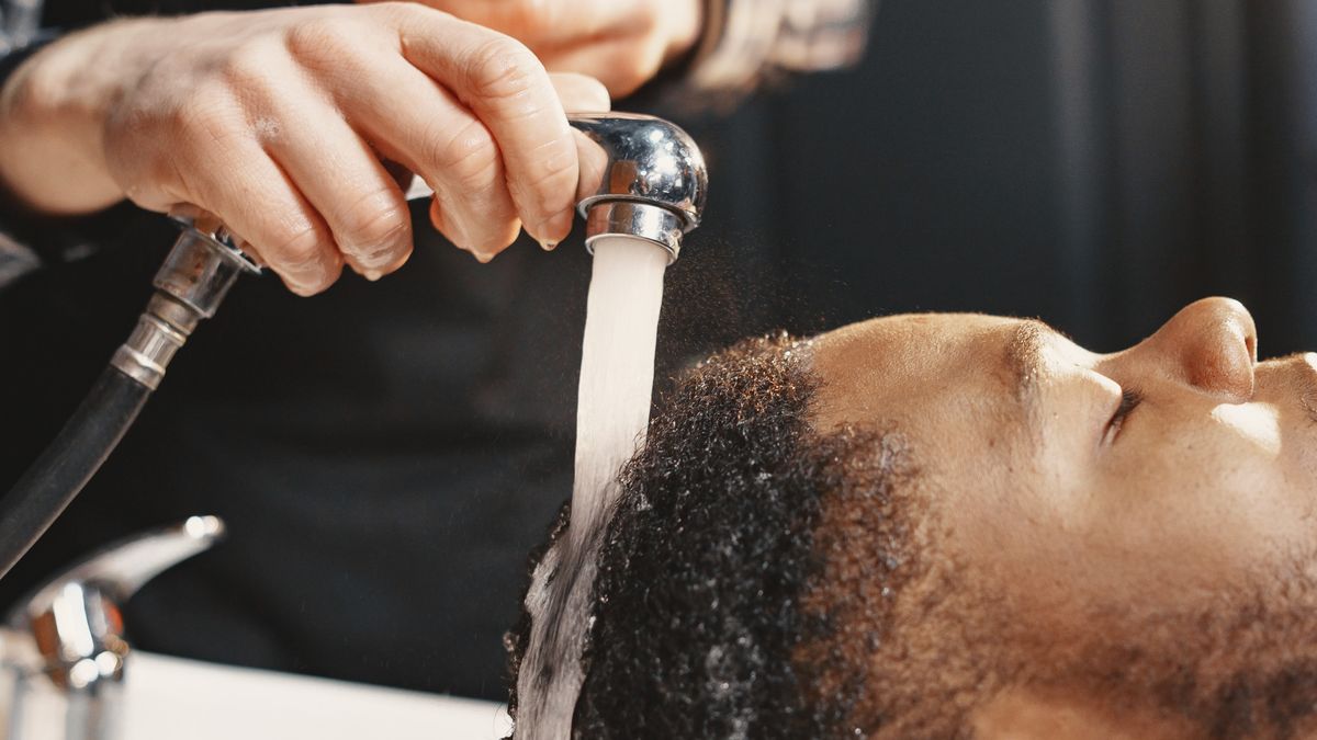 Barber spraying water onto a man's short hair