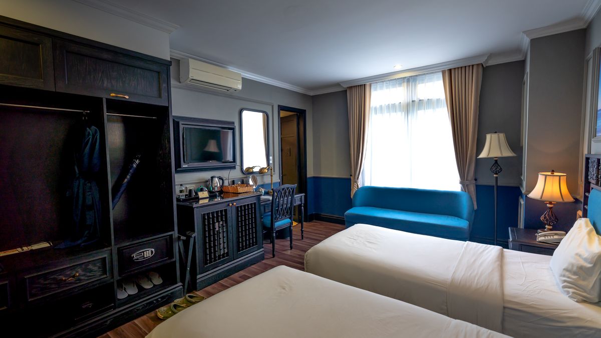 Hotel guest room with an open wardrobe, bedside surfaces, and storage.