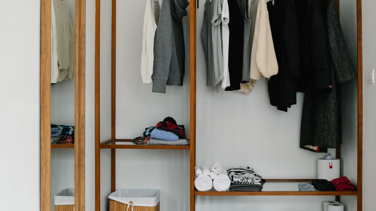 Open wardrobe with hanging clothing, folded garments, towels, and storage shelves.