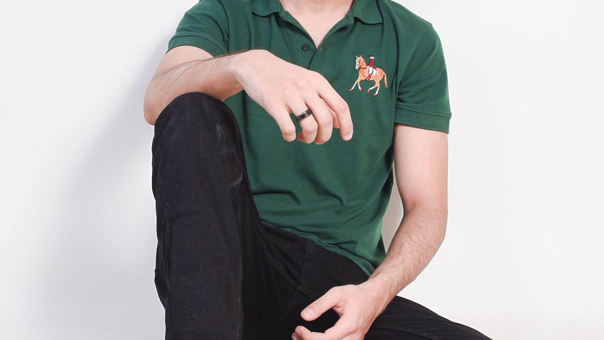 Man seated in a green polo shirt and black trousers