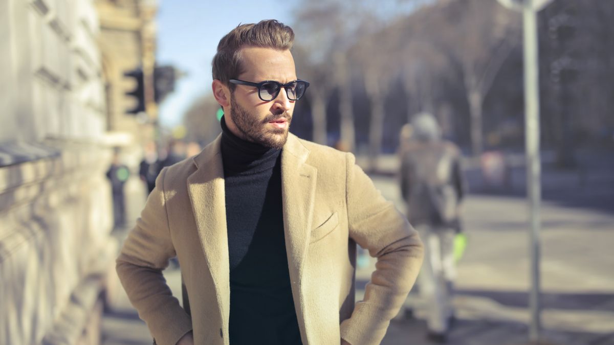 Man in dark turtleneck and coat standing on a city street