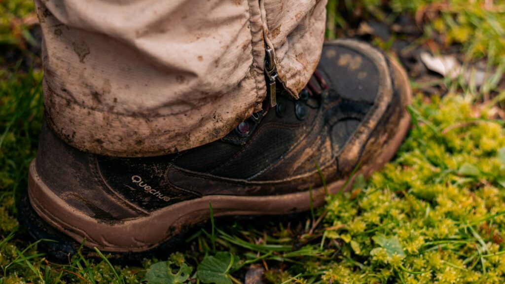 Muddy hiking boot in grass