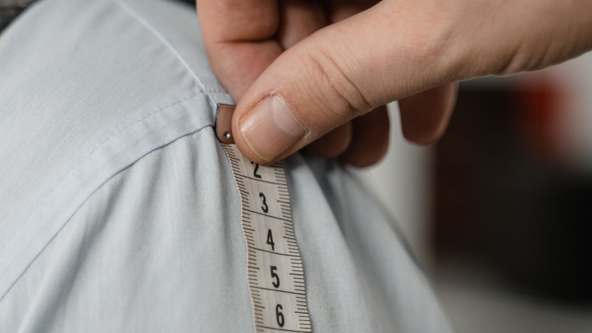 Tailor measuring a man's shirt and upper body