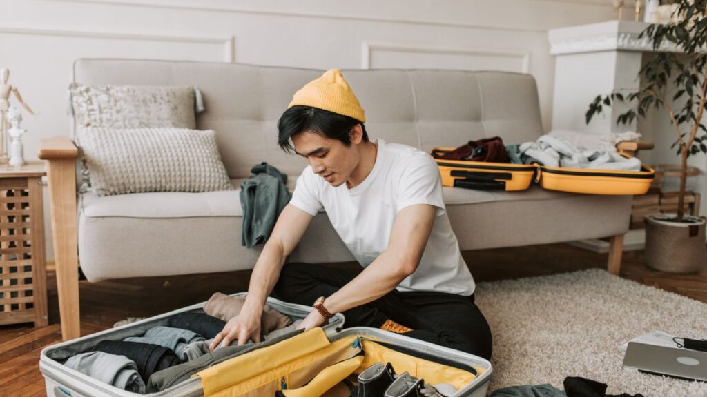 Man organizing clothing in an open suitcase for a three day trip