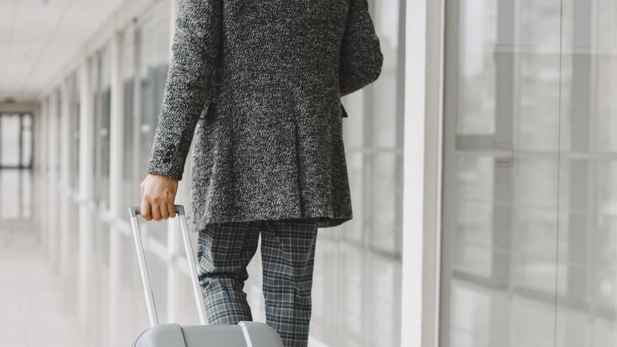 Man in a gray suit traveling with luggage.