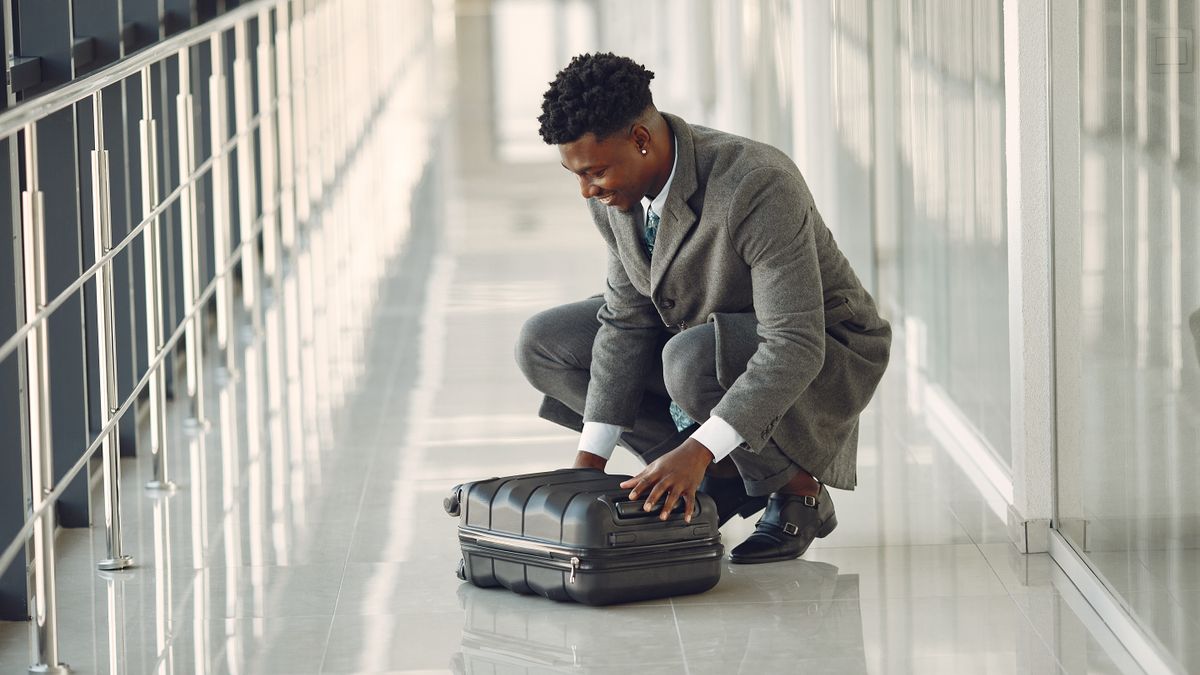 Business traveler standing with suitcase at airport.