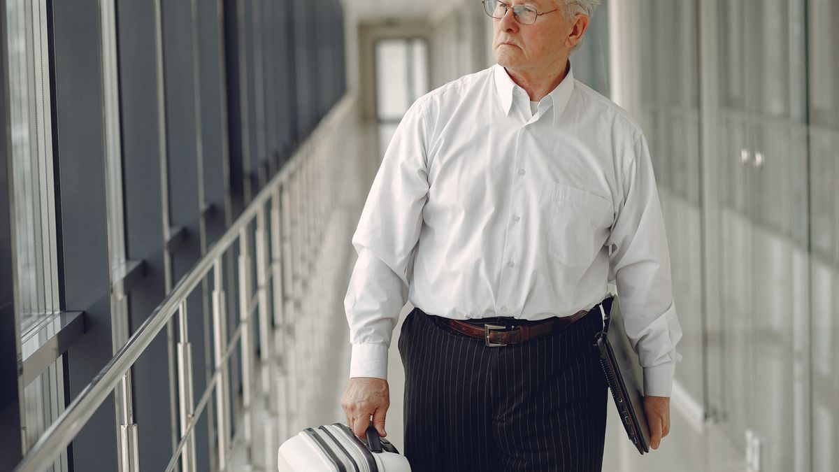 Man with laptop and luggage at airport.