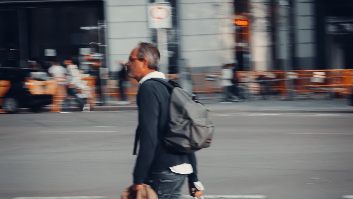 Man walking with luggage through a city.