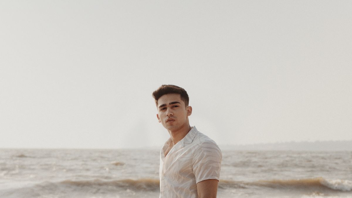 Man standing beside the sea on a sunny day.