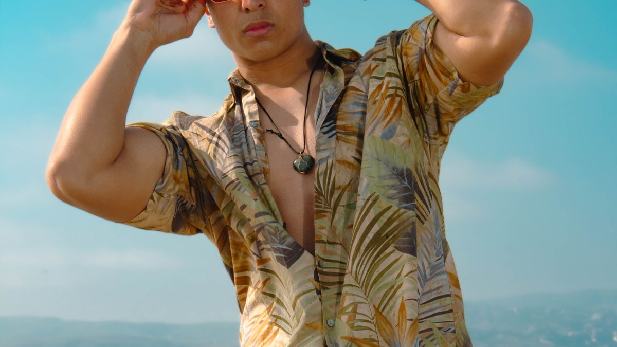 Man in tropical shirt and sunglasses on a beach.