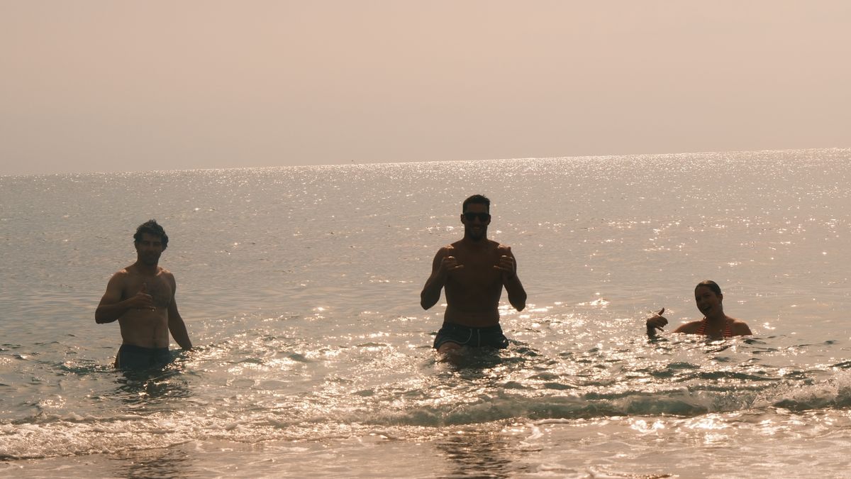 Three men enjoying ocean waves.