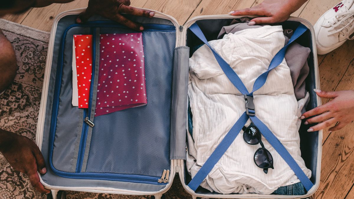 Packed suitcase with clothing and travel accessories.