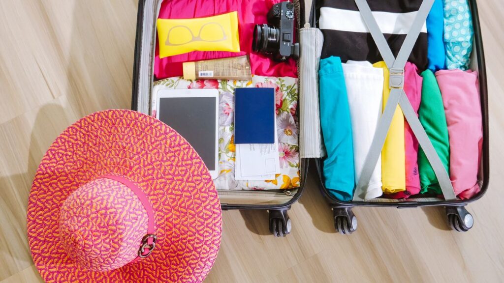Open suitcase with mixed clothing and travel essentials.