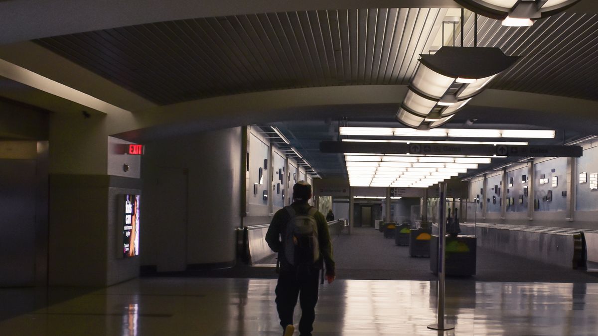 Man with a backpack walking through airport terminal.