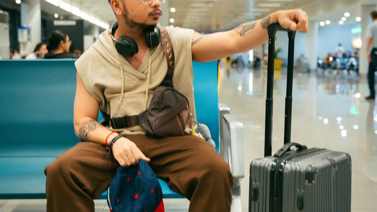 Man waiting in airport terminal with a suitcase.