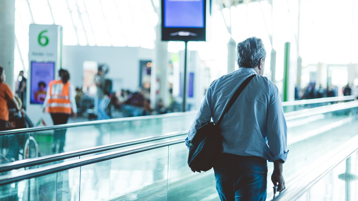 Man walking through an airport terminal travelator.