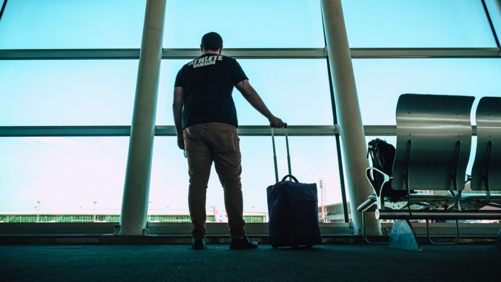 Man waiting in airport lounge with luggage.