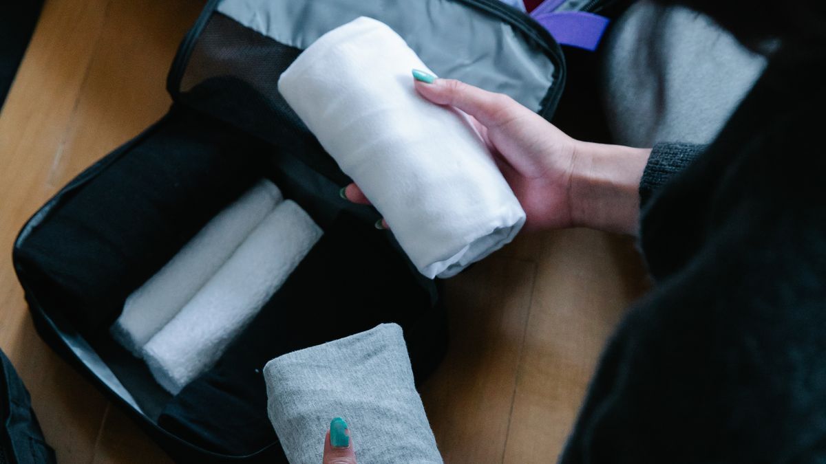 Person organizing clothing inside a suitcase.