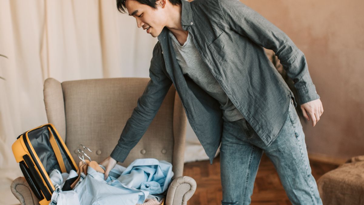 Man organizing clothes inside a suitcase.