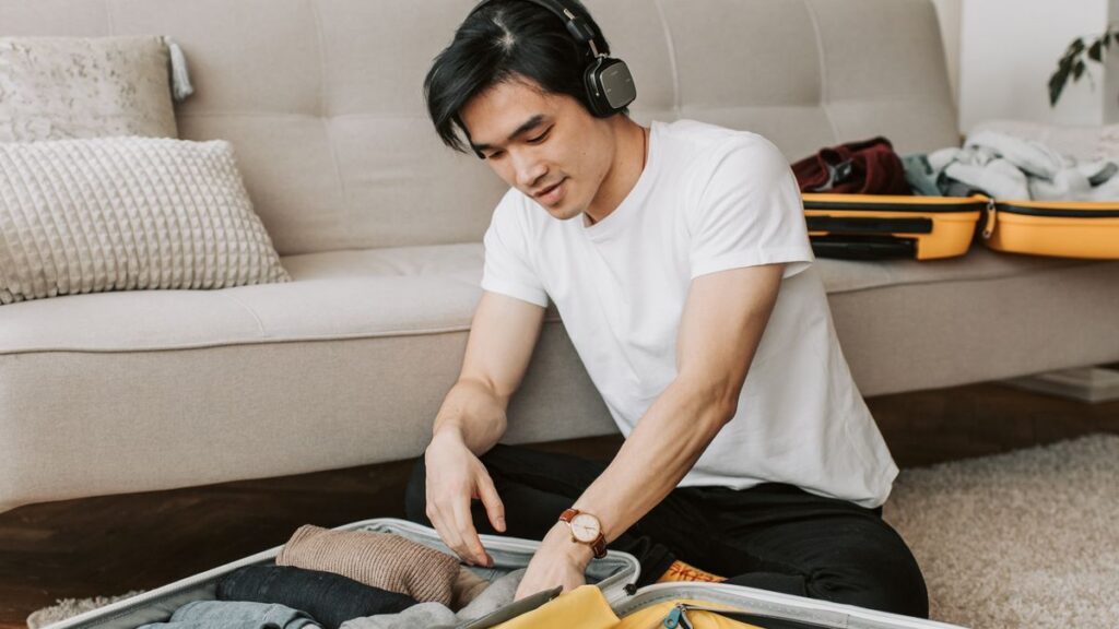 Man packing a suitcase with clothing at home.
