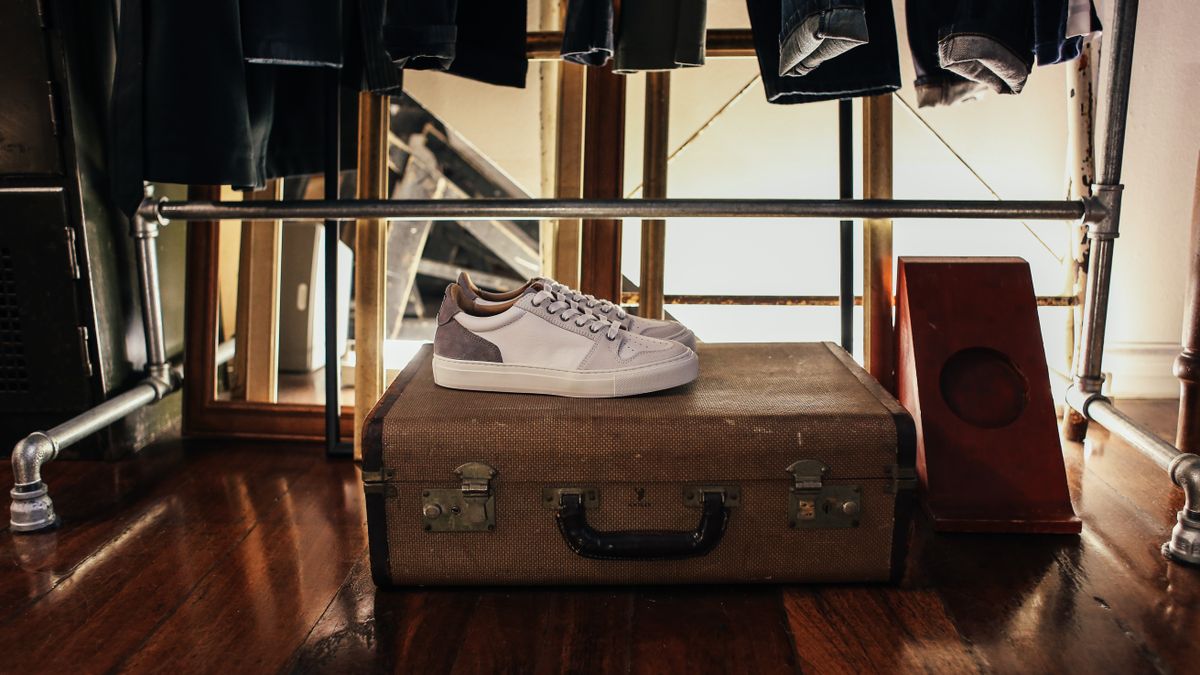 White sneakers on top of a vintage suitcase.