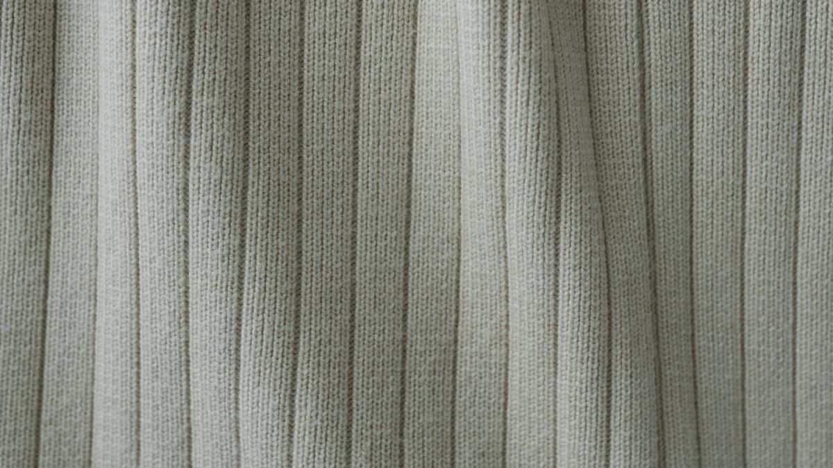 Cream cardigan hanging from a wooden hanger