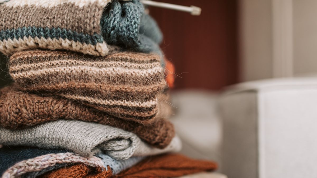 Several neatly folded sweaters stacked on a shelf