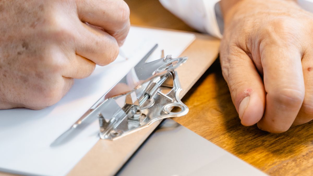 Hand filling in a paper form with a pen