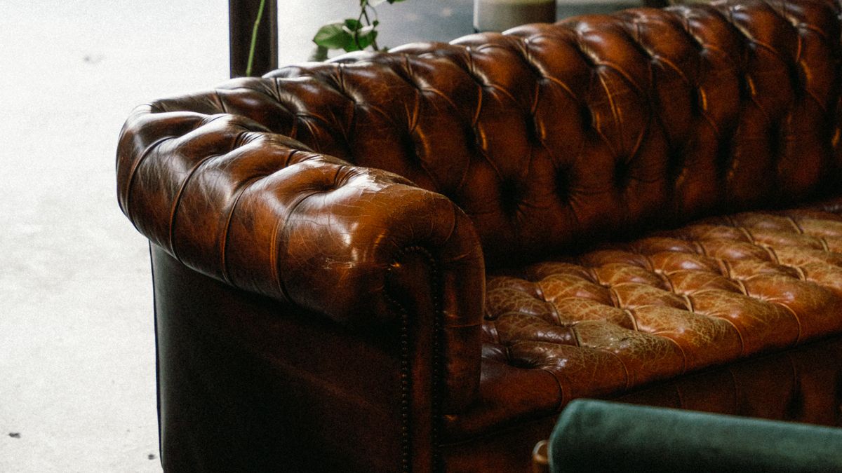 A vintage leather sofa in an industrial garage beside automotive elements