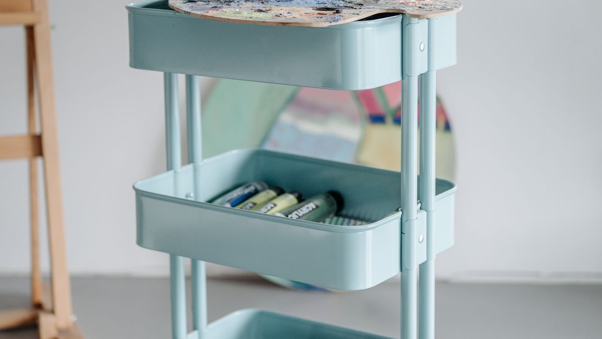 A mobile three-tier art-supply cart illustrates flexible storage in a hobby room