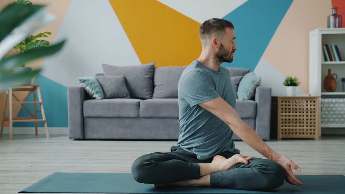 A man practising yoga in his living room