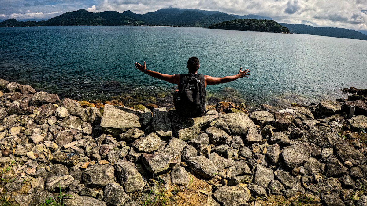 Man with arms outstretched by the sea while taking time off.