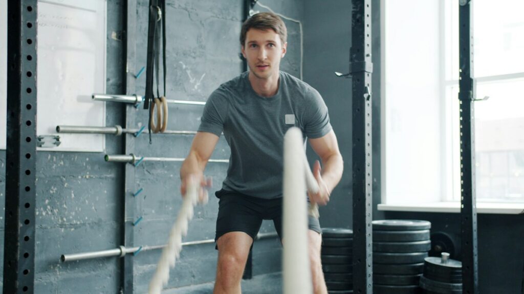 Man training with battle ropes in a gym, fitness context