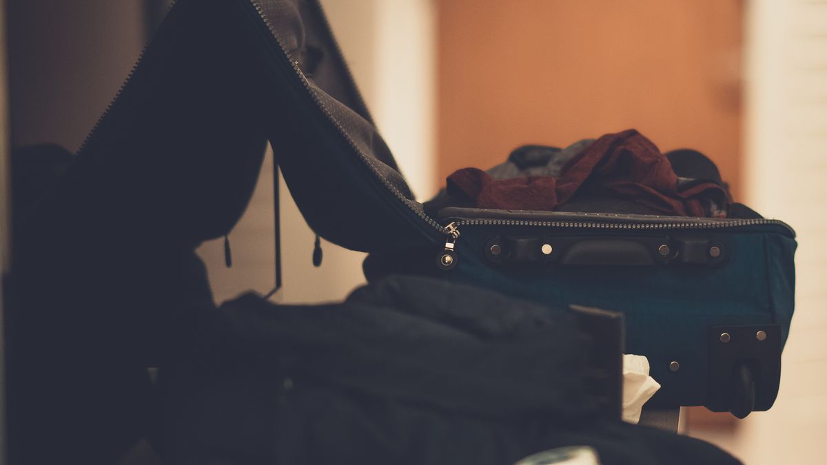 Open dark blue suitcase with folded clothing in a softly lit room.
