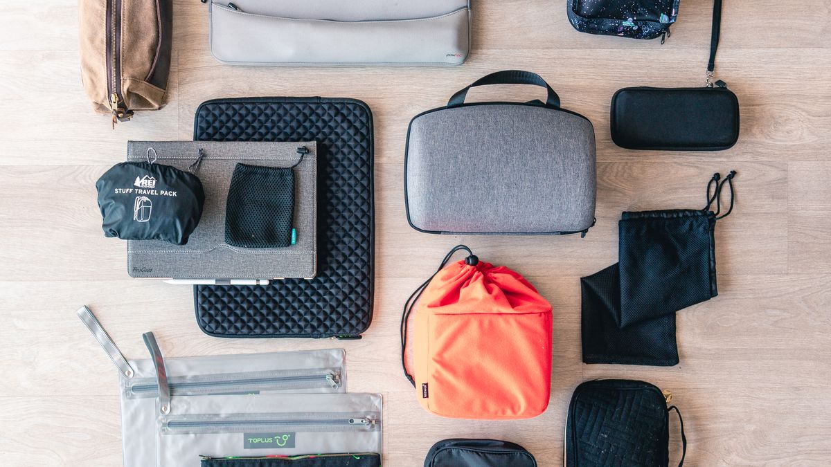 Travel accessory pouches and organizers laid out on a wooden floor.
