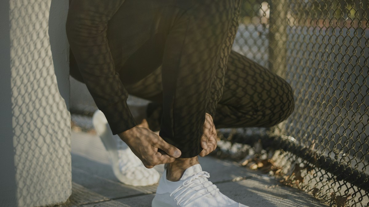 Man tying athletic shoes on the pavement before a run