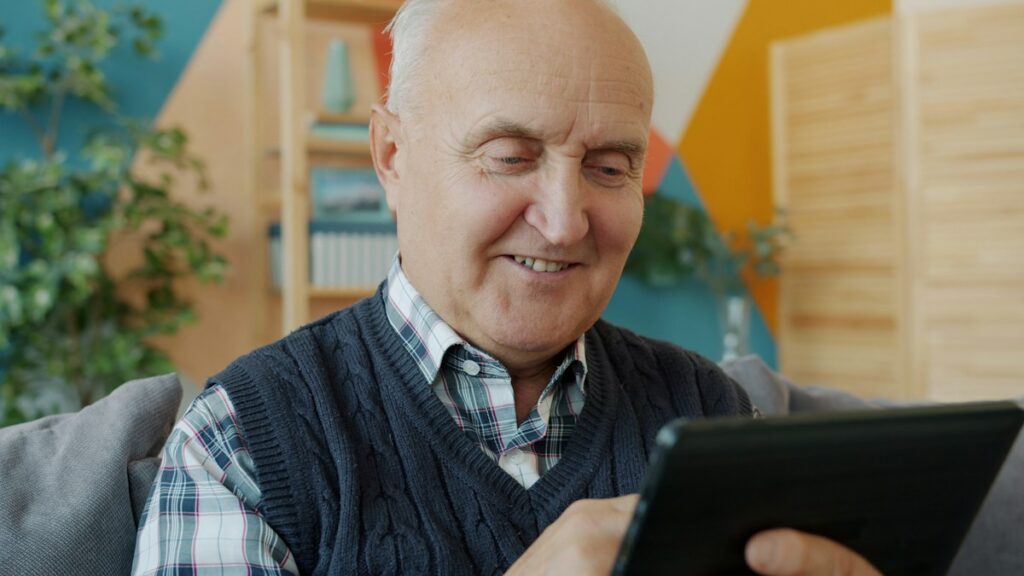 Older man seated at home looking at a tablet