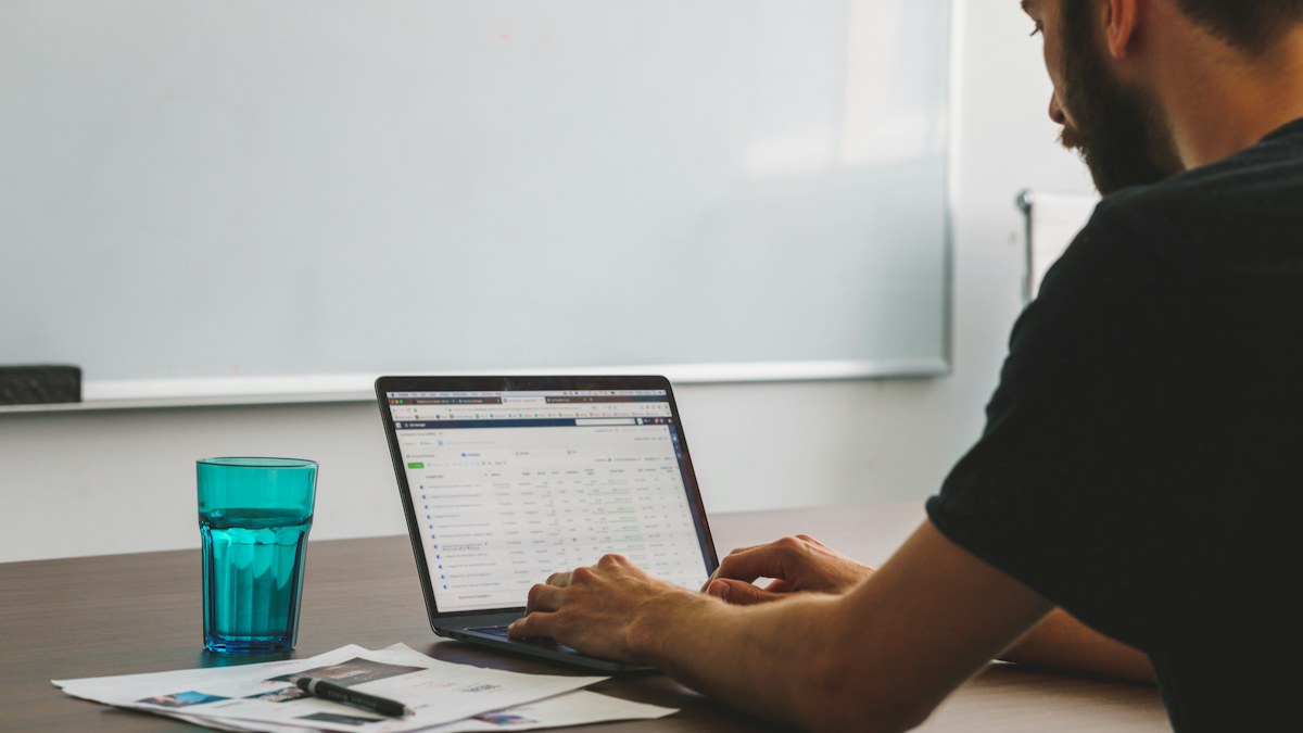Man working at a desk while planning tasks on a laptop